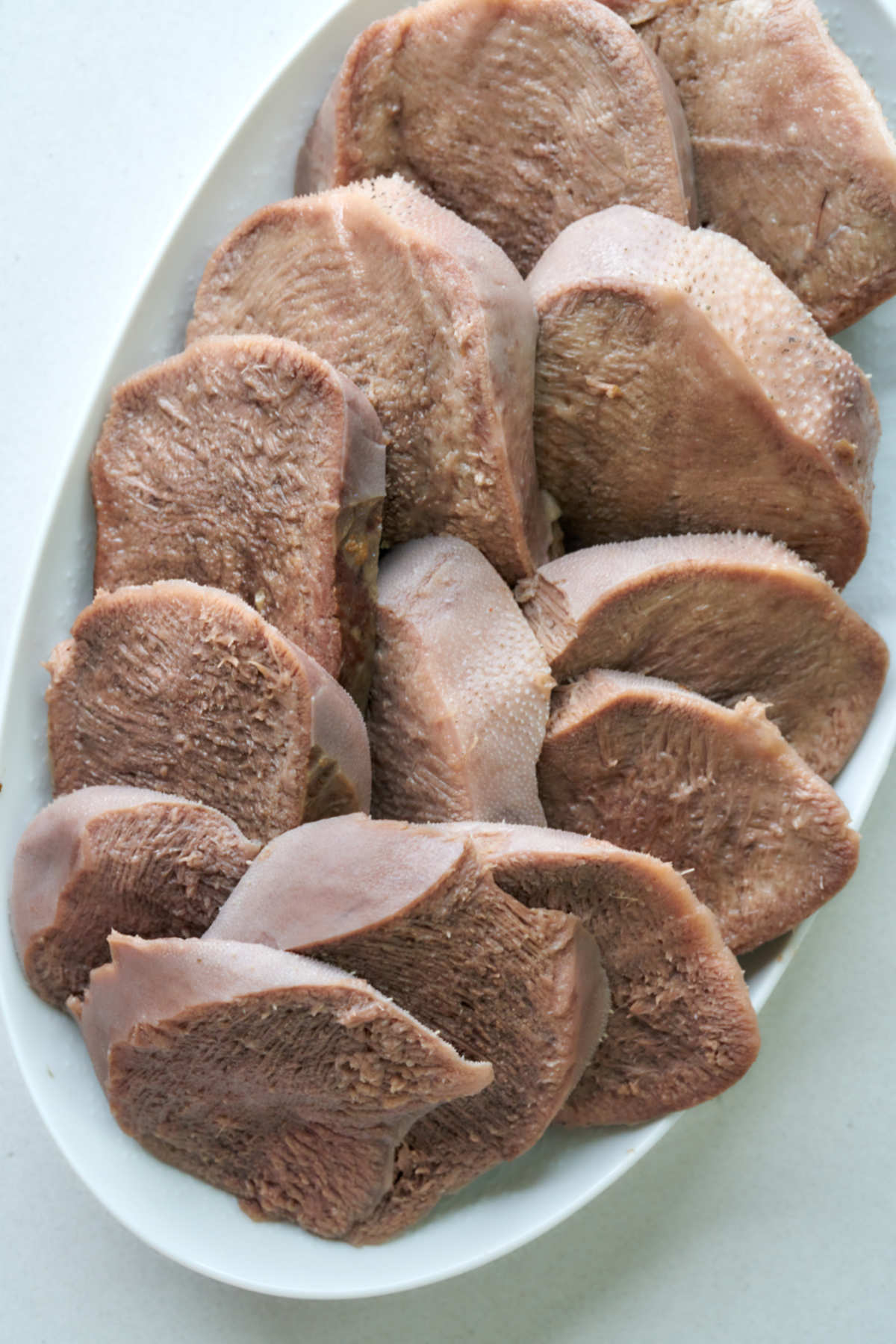 Top view of sliced cow tongue on a plate.