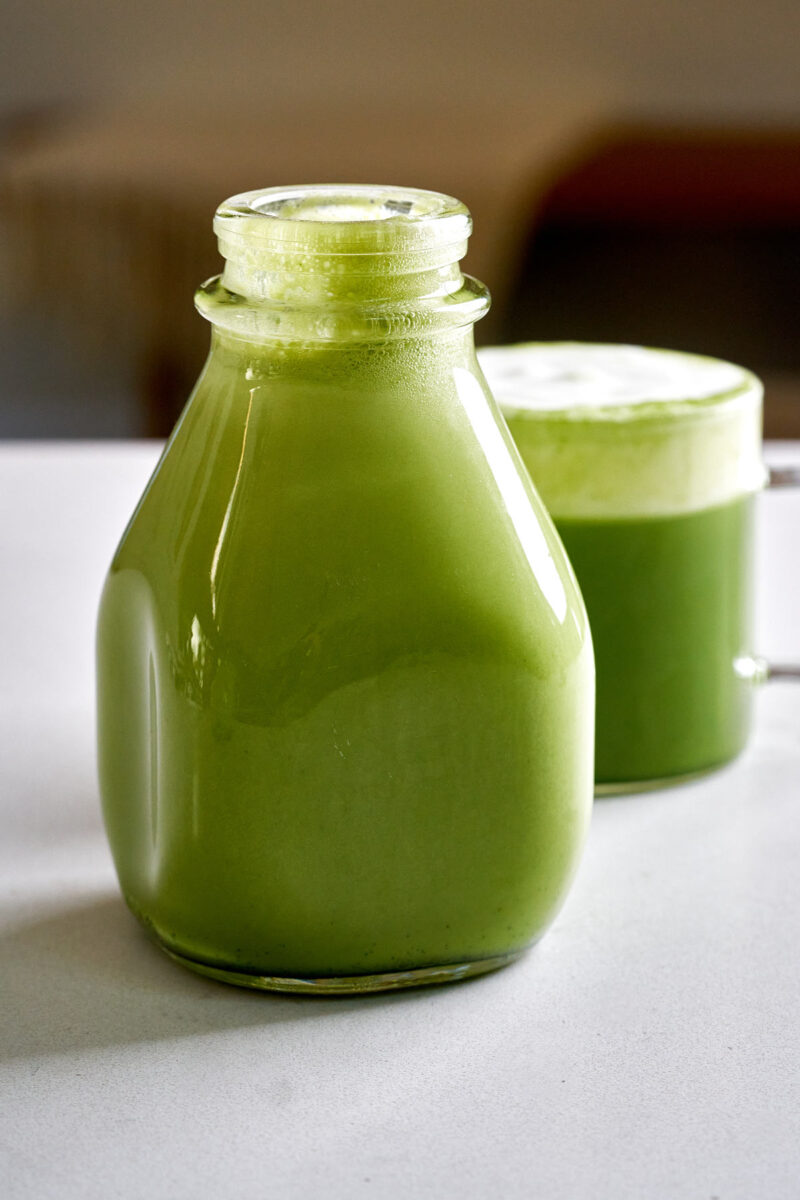 Milk jug filled with green Irish cream next to a spiked matcha.