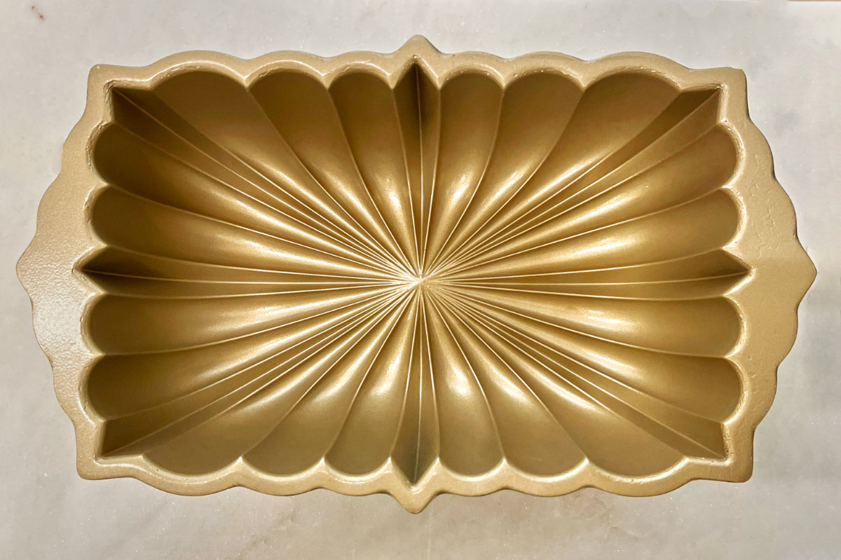 Gold fluted loaf pan on white marble.