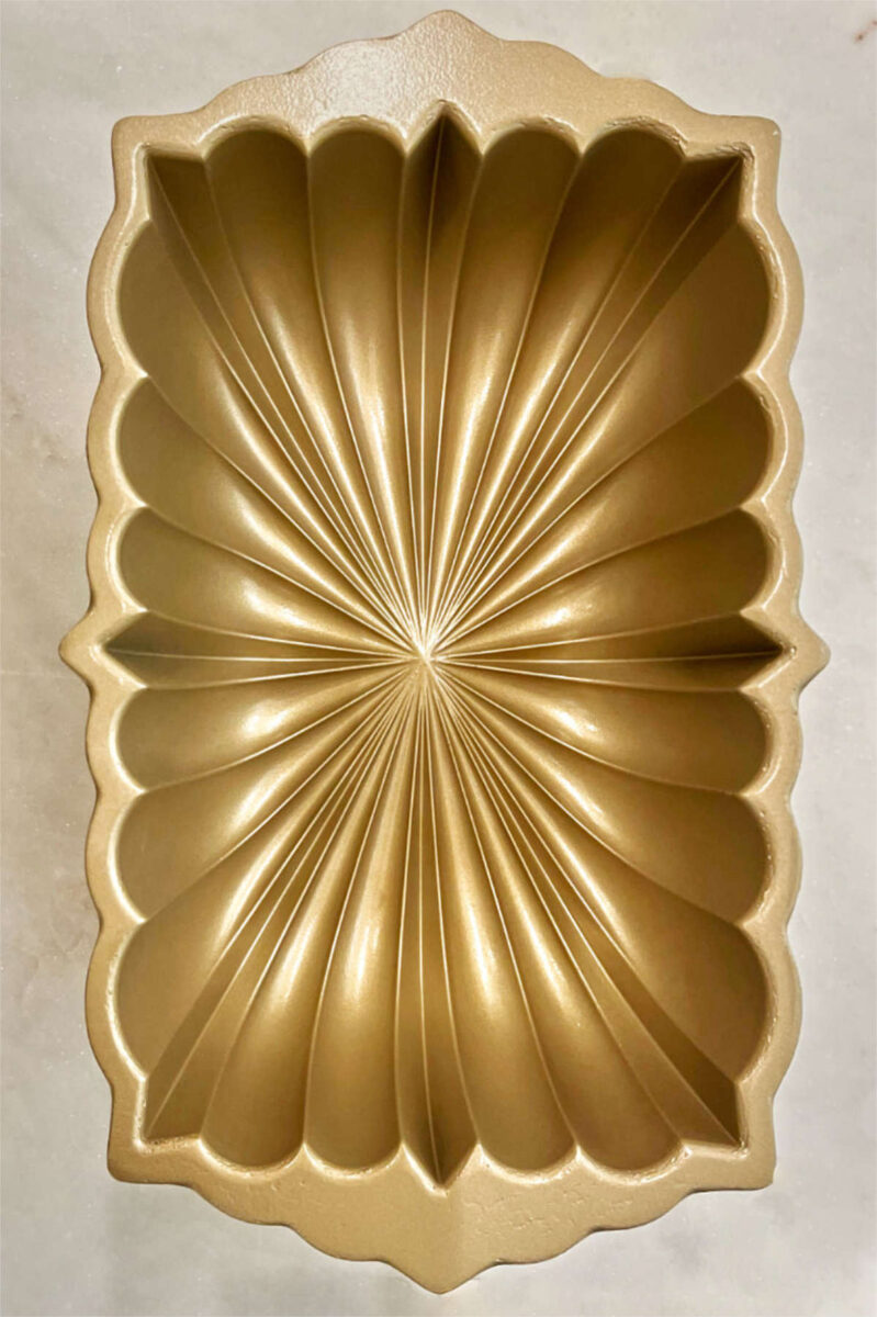 Gold fluted loaf pan on white marble.