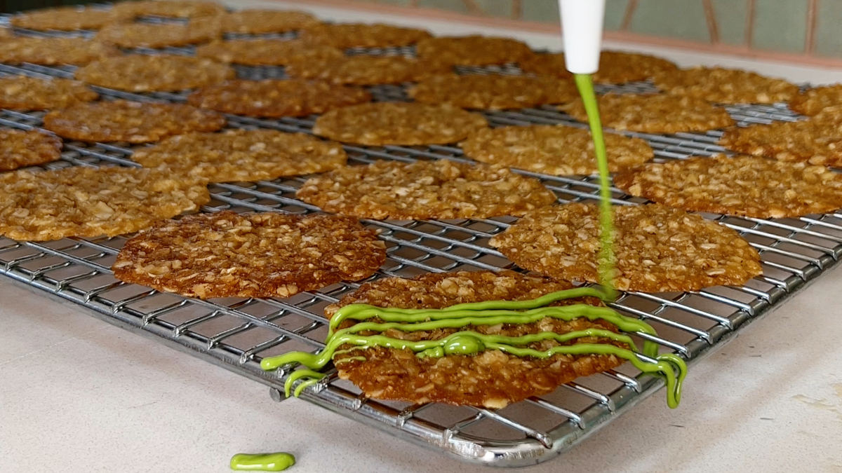 Drizzling green chocolate on a lace cookie.