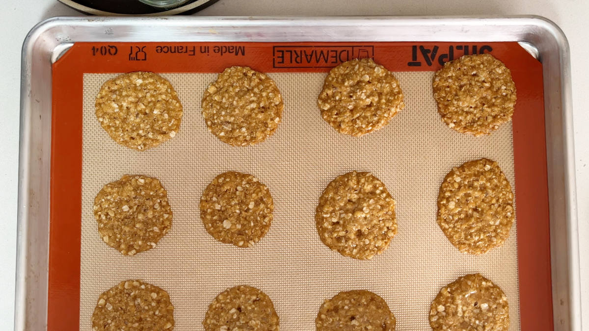 Lace cookies on a baking sheet lined with silicone baking mat.