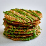 Stack of lace cookies with green chocolate drizzle.