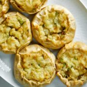 Top view of six potato knishes on an oval plate.