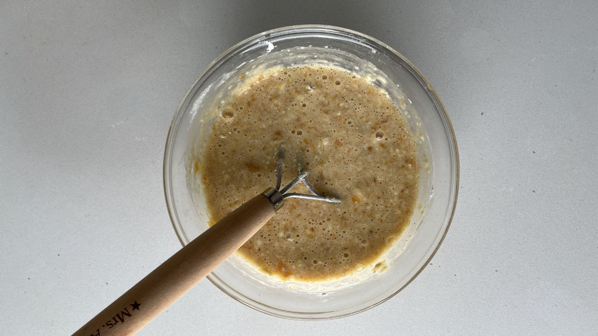 Batter in a glass bowl with a dough whisk.