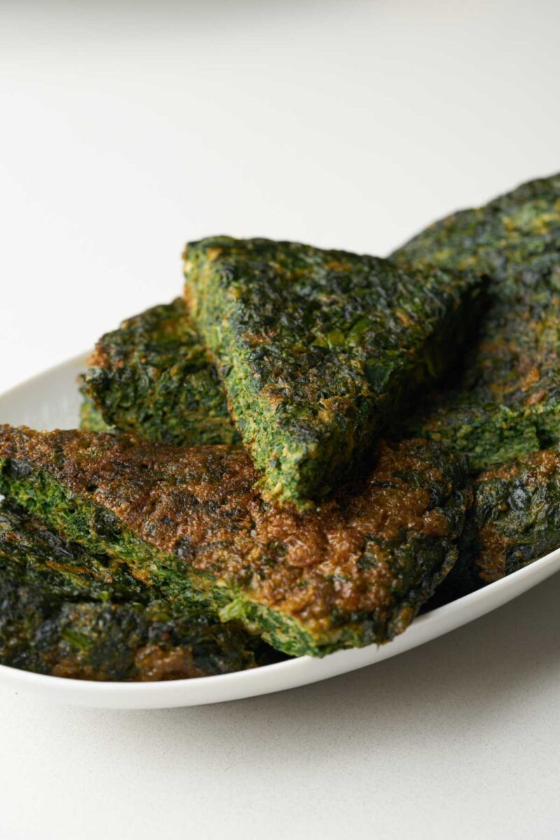 Front view of wedges of kuku sabzi on a plate.