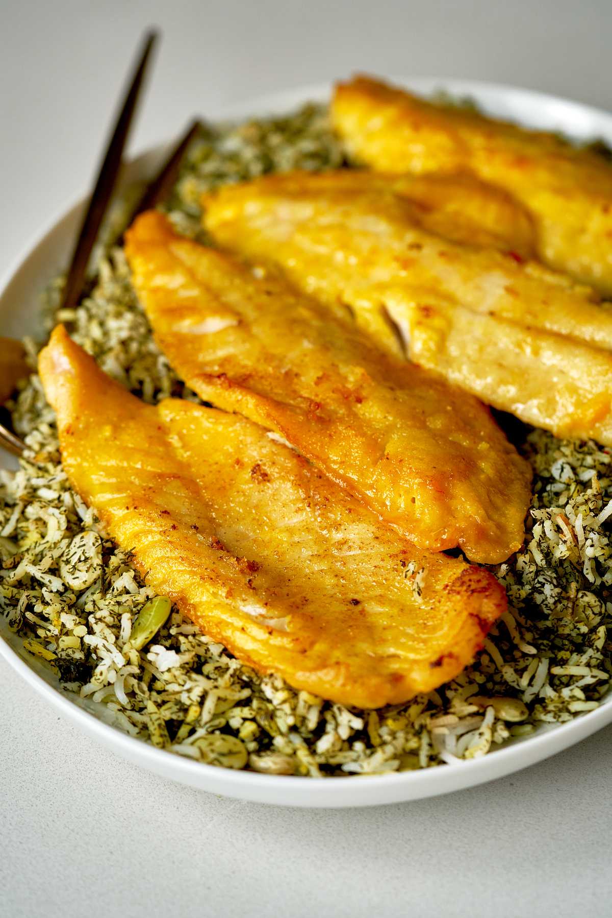 Fried fish on top of green rice.