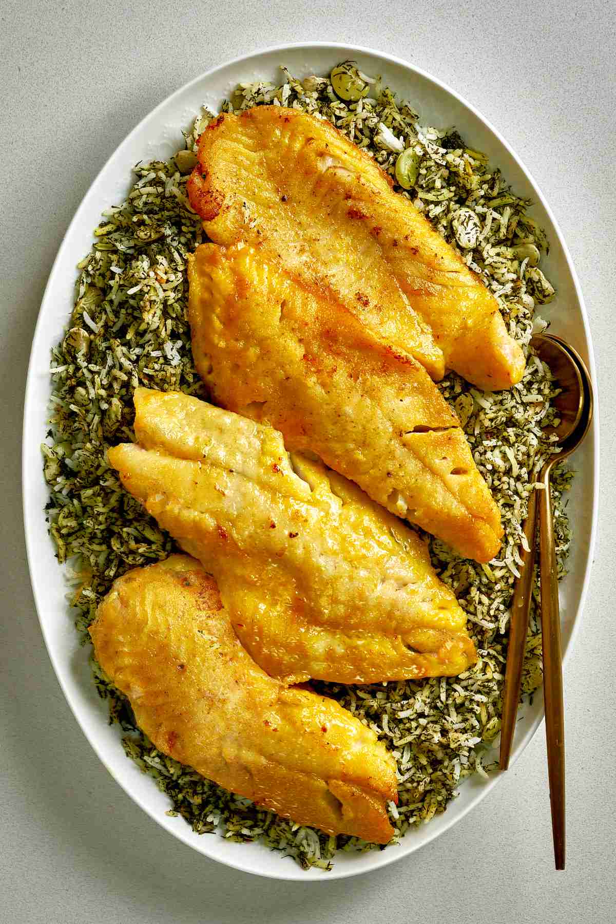 Fried fish on top of green rice.