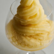 Yellow soft serve in a cognac pedestal glass.