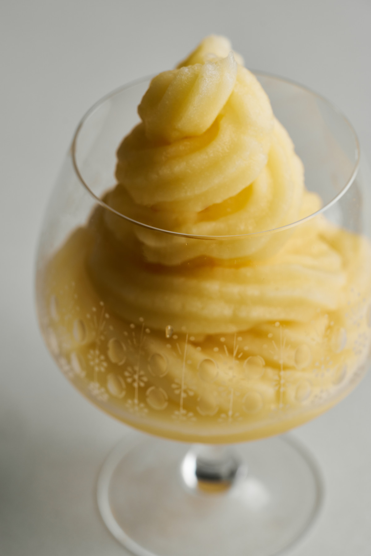 Yellow soft serve in a cognac pedestal glass.
