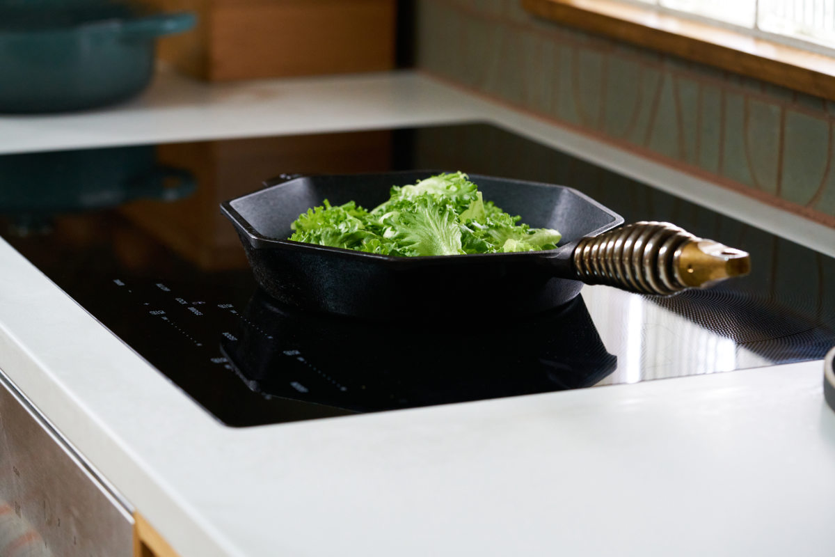 Black induction cooktop with cast iron pan.