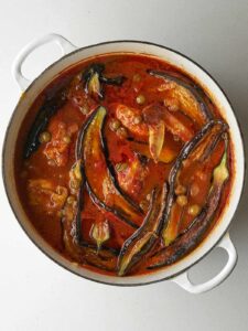 Top view of cooked eggplant stew with chicken in red sauce.