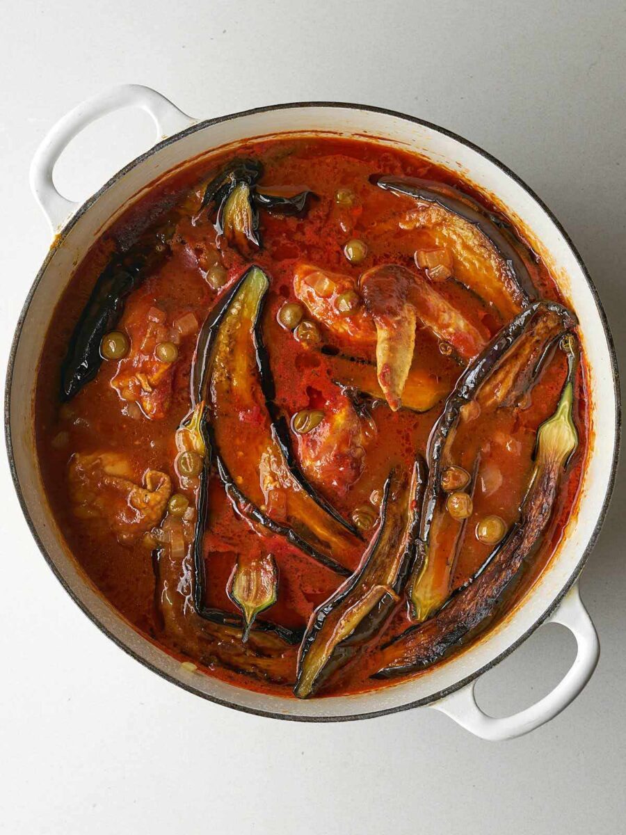 Top view of cooked eggplant stew with chicken in red sauce.