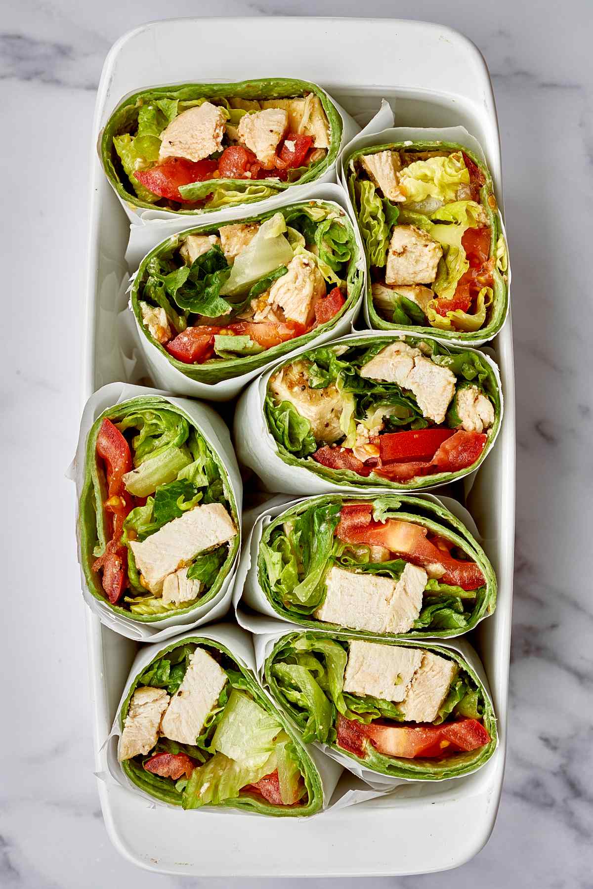 Caesar salad wraps cut in half and placed together in a white dish.