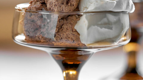 Mousse and whipped cream in a brown pedestal glass.