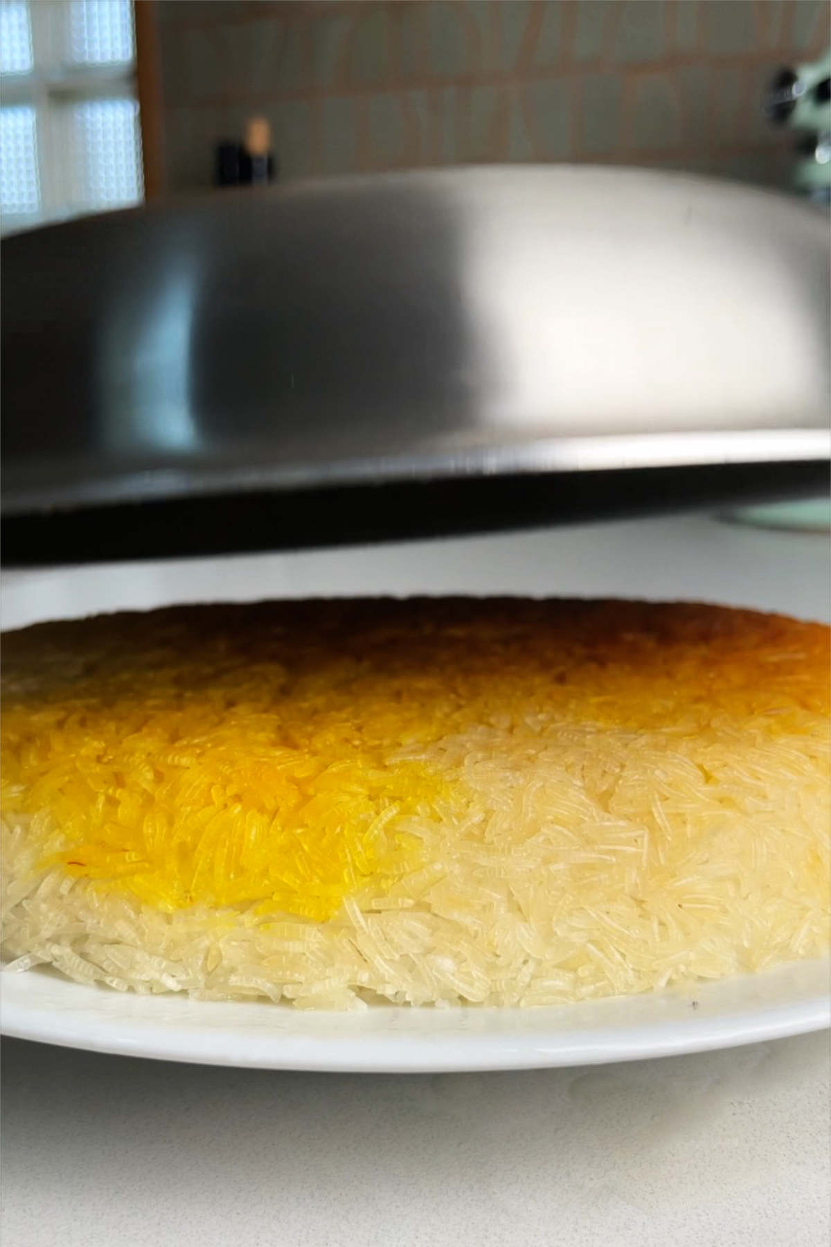 Crispy rice on a white plate with an upside down fry pan hovering over it.