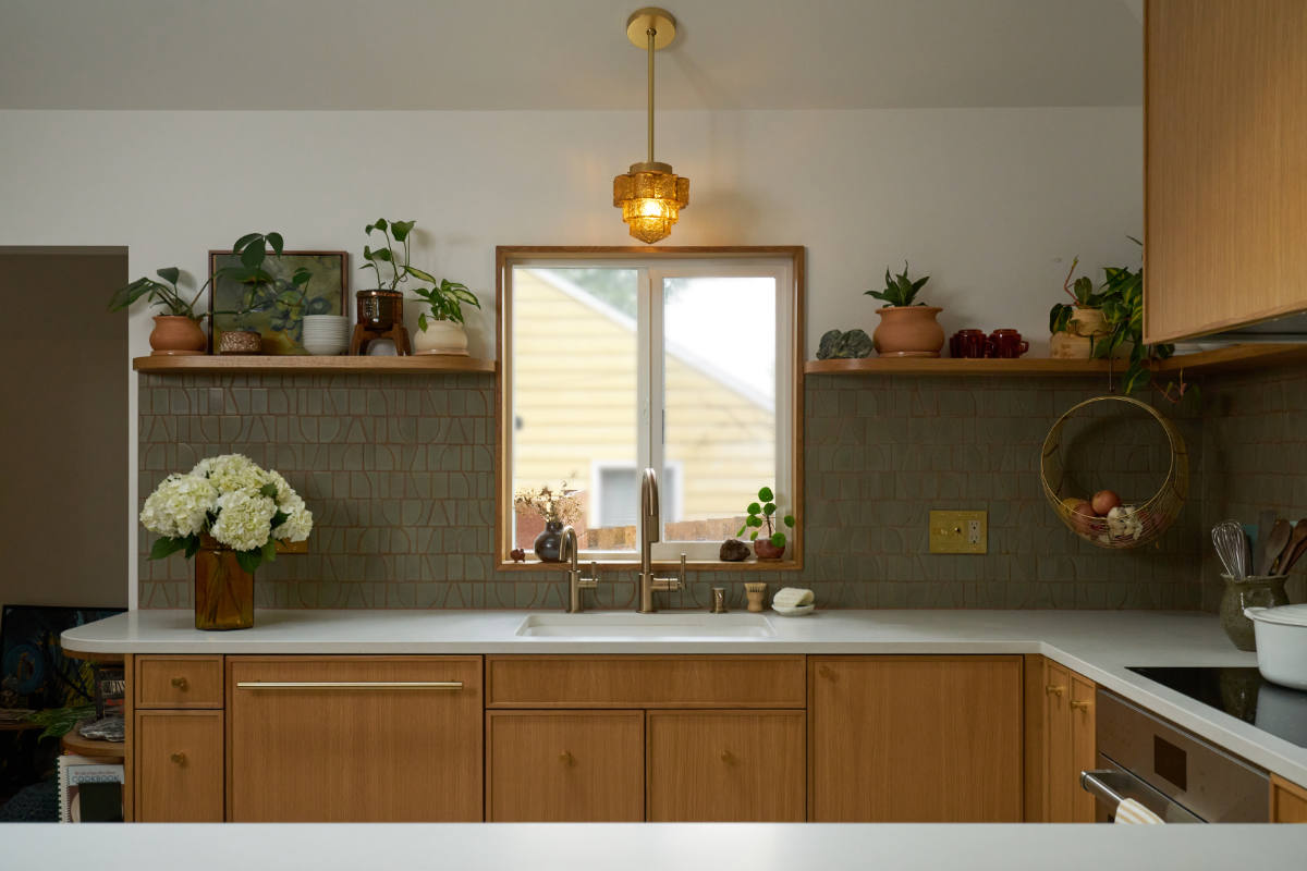 Green mosaic backsplash with wooden cabinets and sink.