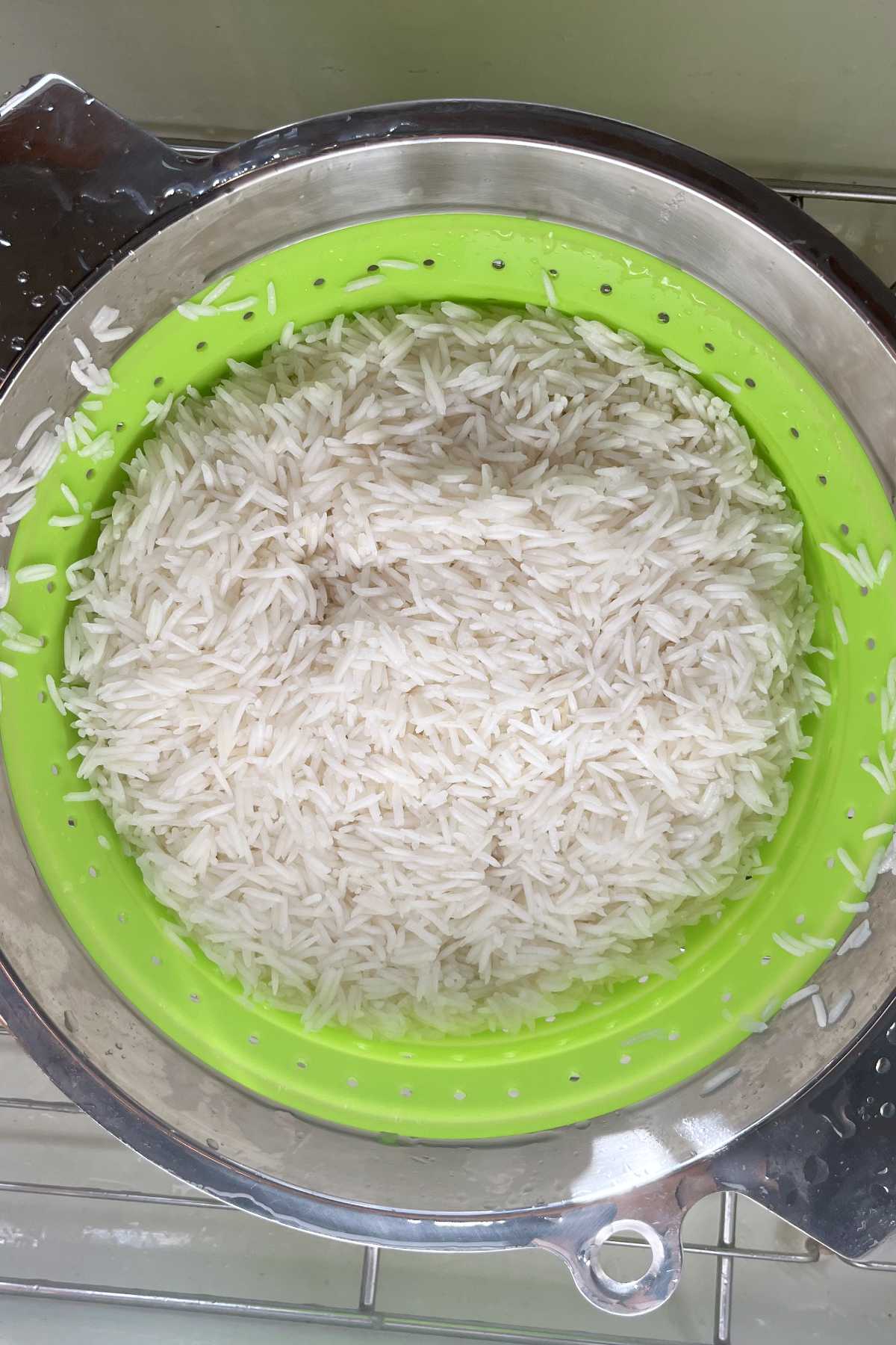 Rice in a green and metal colander.
