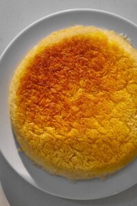 Crispy yellow tahdig on a white plate.