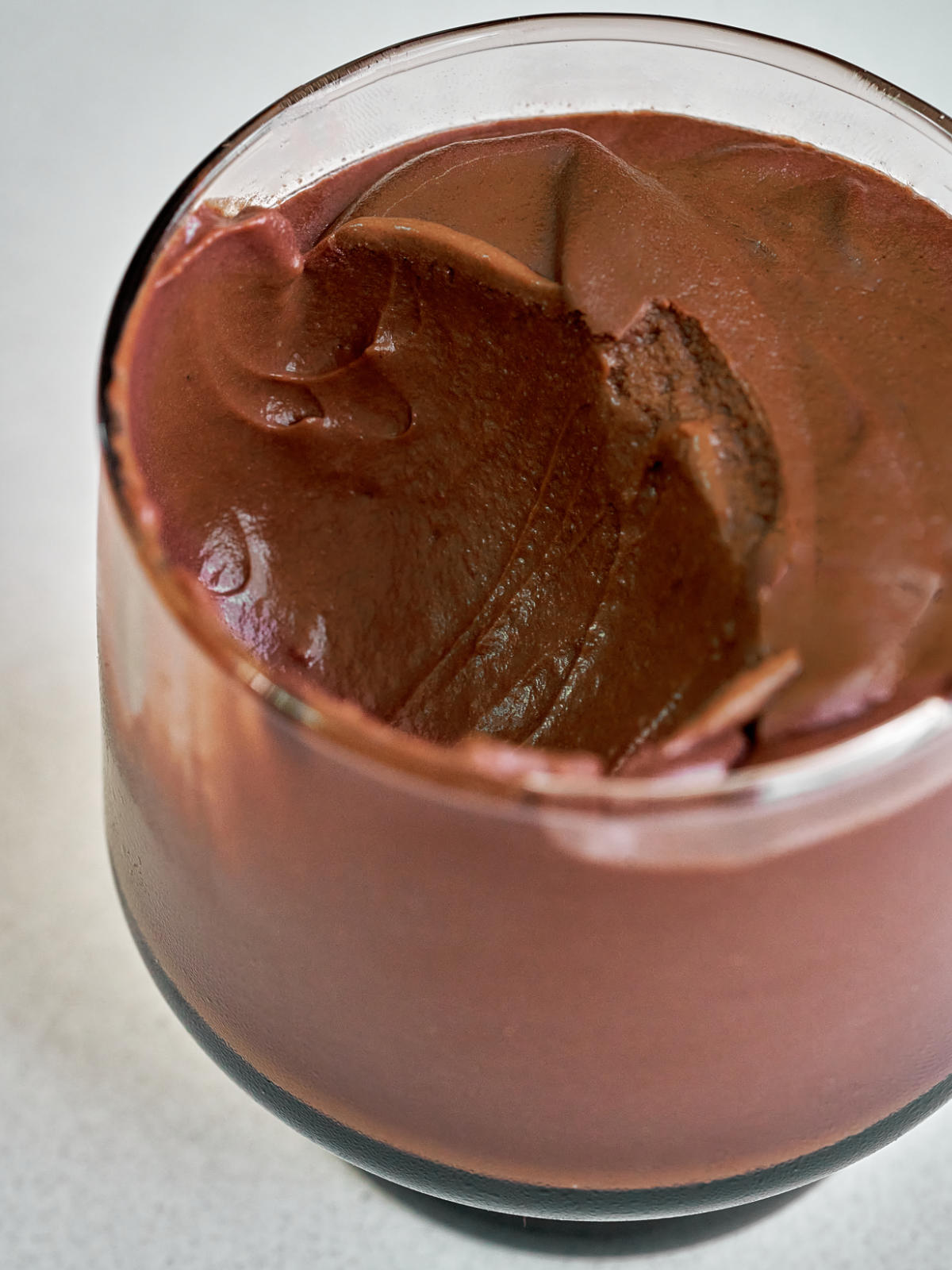 Chocolate pudding in a small glass with a large spoonful taken out.