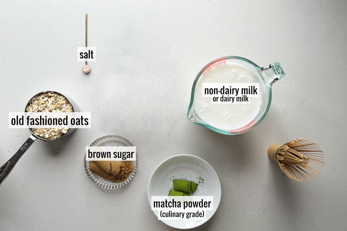 Milk, matcha green tea powder, oats, and other labeled ingredients on a countertop.