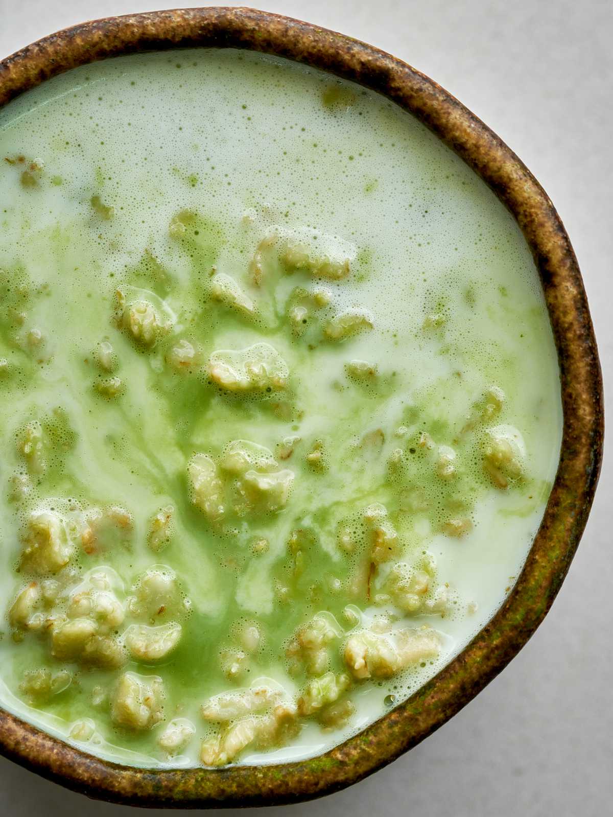 Green swirled runny oatmeal in a matcha bowl.