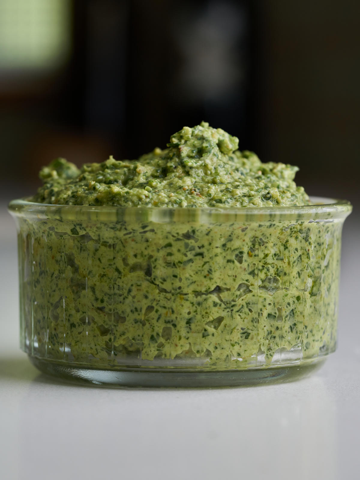 Green pesto in a glass ramekin.