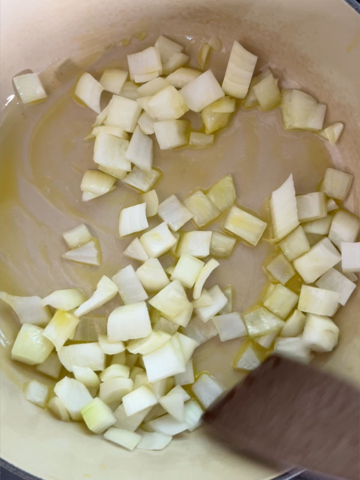 Diced onion in an enameled cast iron pot.