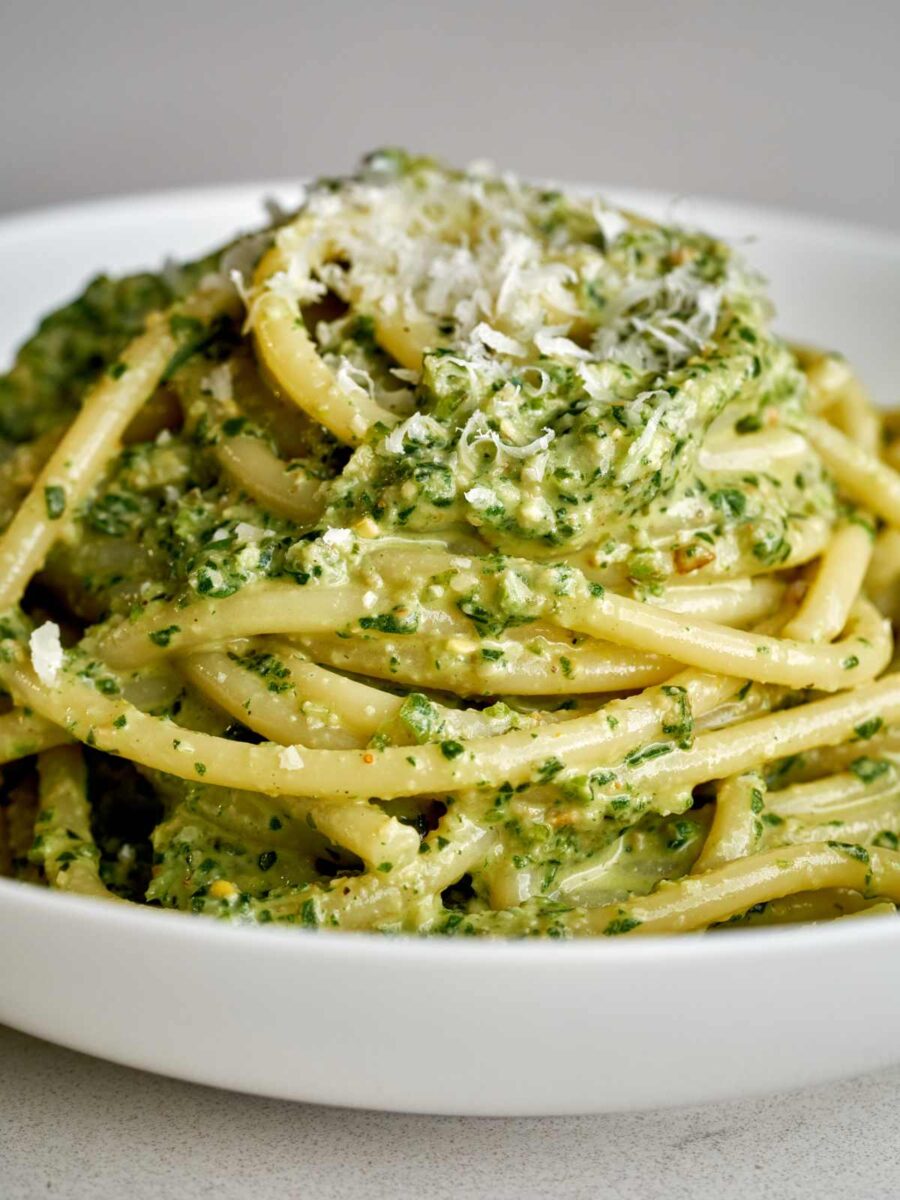 Pesto pasta in a white pasta bowl and topped with parmesan.