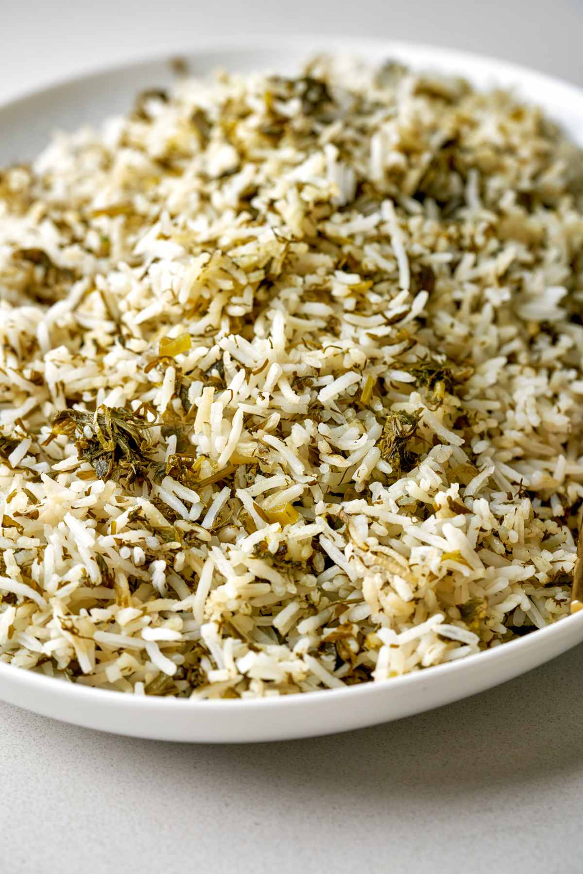 Rice mixed with herbs on an oval white platter.