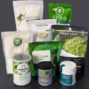 9 packages of matcha on a black countertop with a black background.