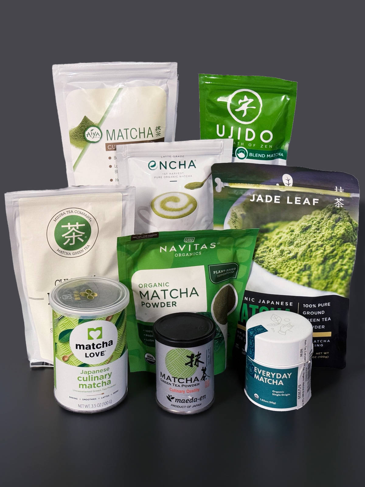 9 packages of matcha on a black countertop with a black background.