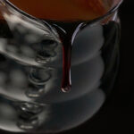 Pouring a thick dark burgundy liquid out of a glass pitcher.