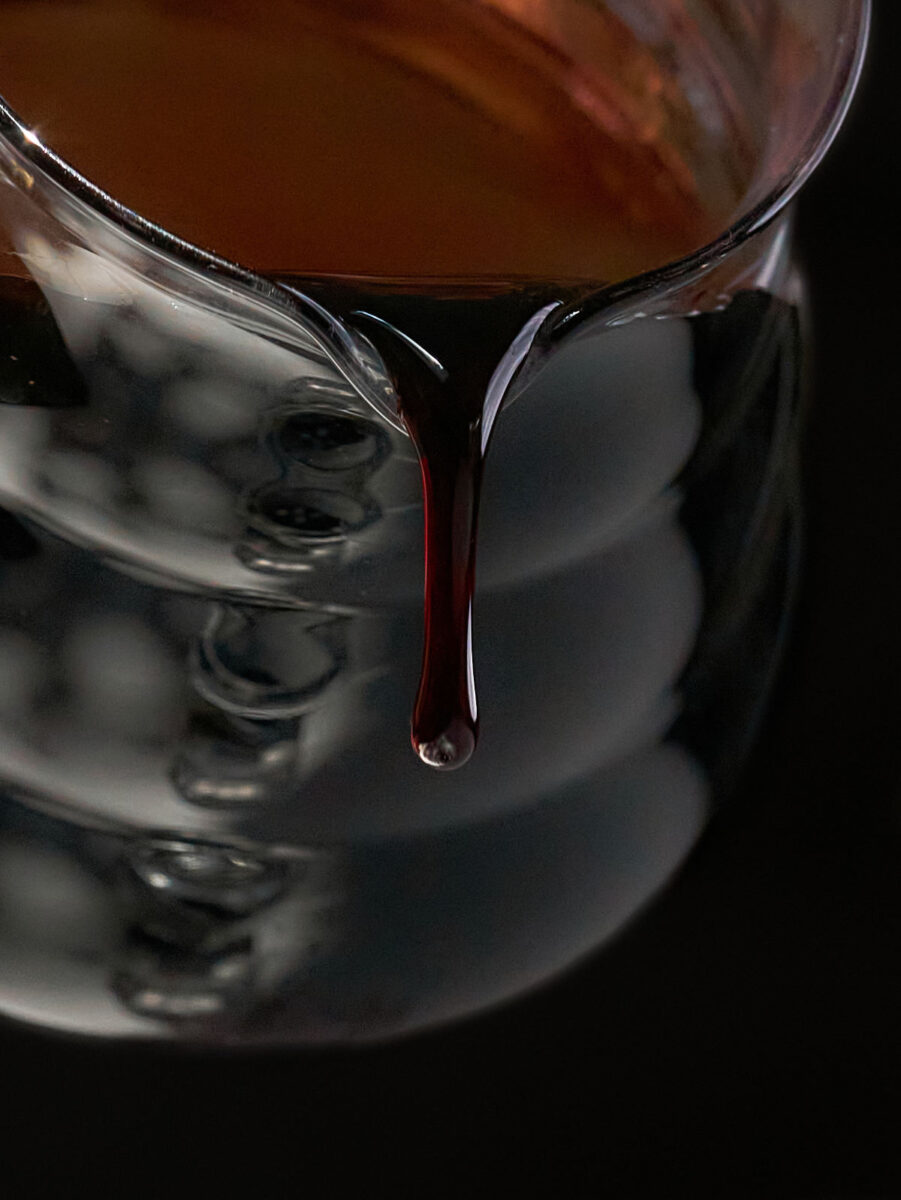 Pouring a thick dark burgundy liquid out of a glass pitcher.