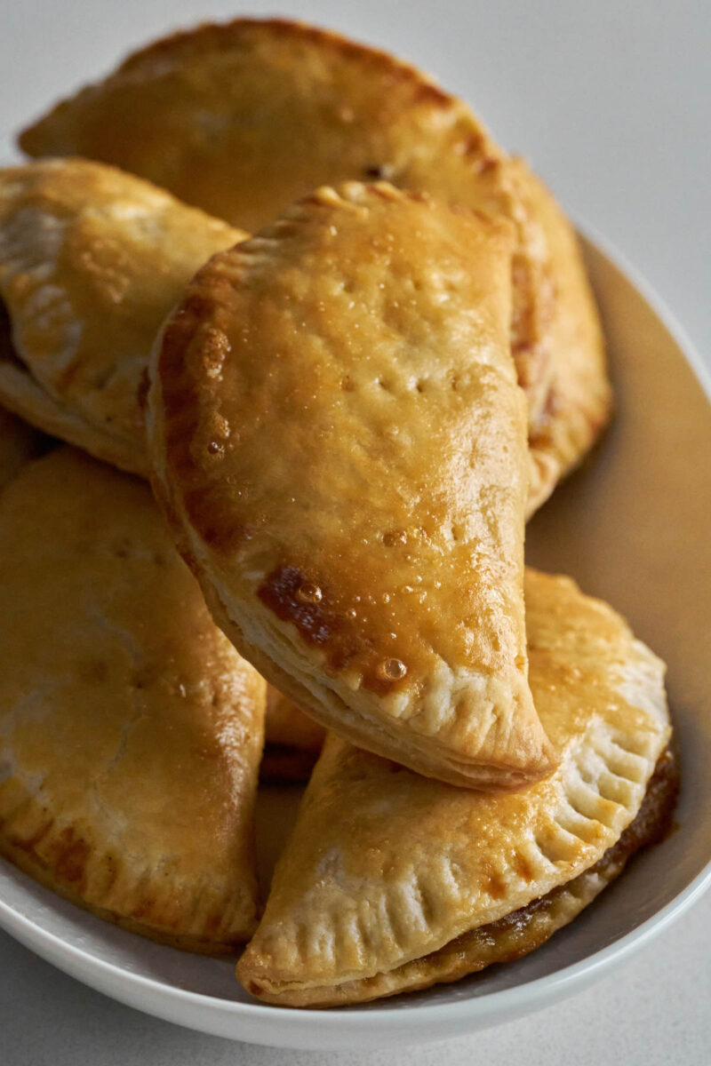 Pile of half-moon shaped hand pies on a white plate.