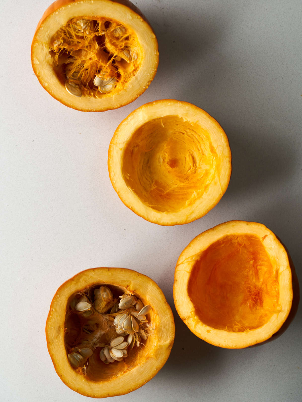 Two pumpkins cut in half with two halves still with seeds.