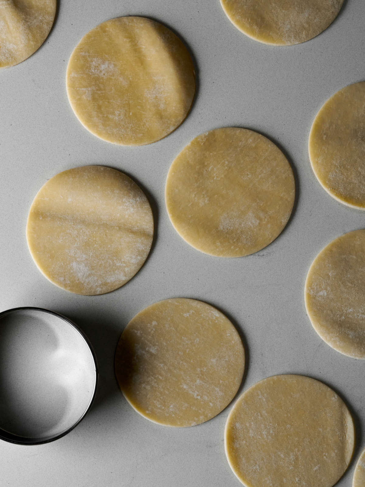Circles of pie dough on a countertop next to a cookie cutter.