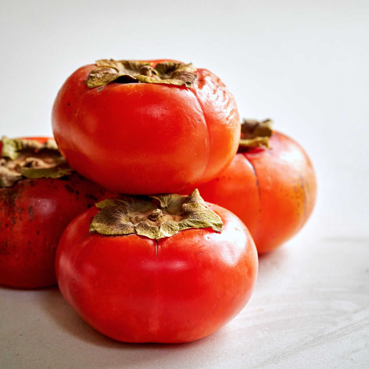 Stack of dark orange persimmons.