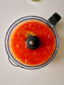 Food processor bowl filled with orange puree.