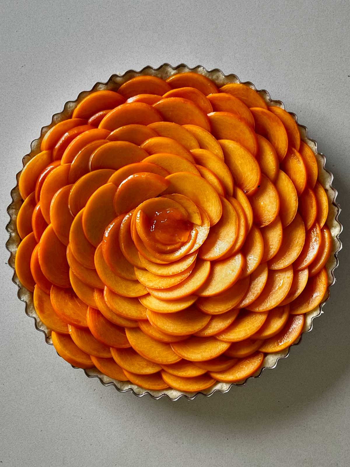 Persimmon arranged in a rose pattern in a round tart pan.