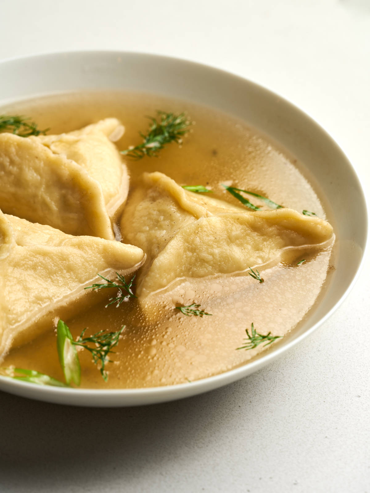 Triangular kreplach dumplings in chicken broth with fresh herbs.