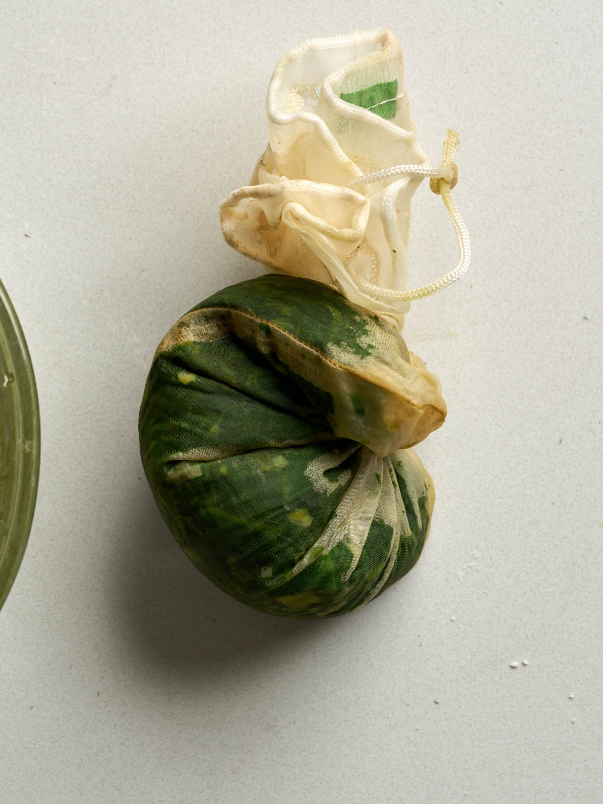 Green herbs squeezed inside a cheesecloth