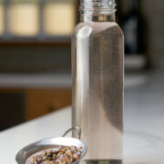 Glass bottle filled with simple syrup next to a small strainer with lavender flowers.