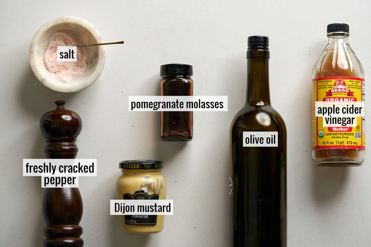 Pomegranate molasses, apple cider vinegar, and other ingredients to make a salad dressing on a countertop.