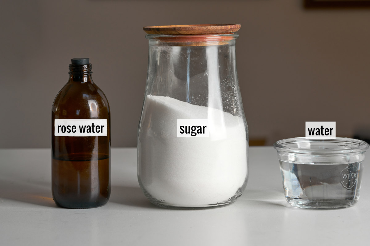 An amber bottle next to a jar of white sugar next to a jar of water.