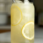 Lemonade in a beer can glass with lemon slices next to lavender buds.