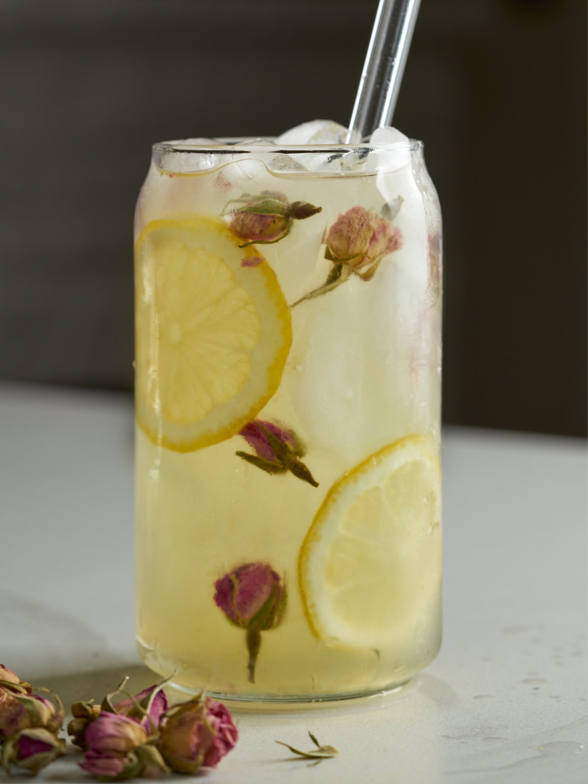 Lemonade in a beer can glass with rose buds and lemon slices.