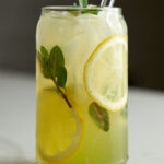 Lemonade in a beer can glass with lemon slices and fresh mint.