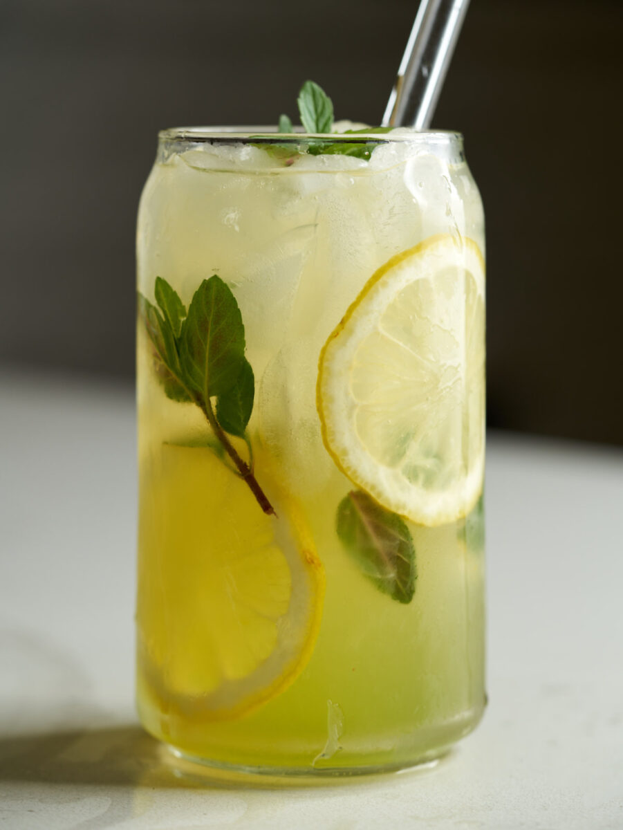 Lemonade in a beer can glass with lemon slices and fresh mint.