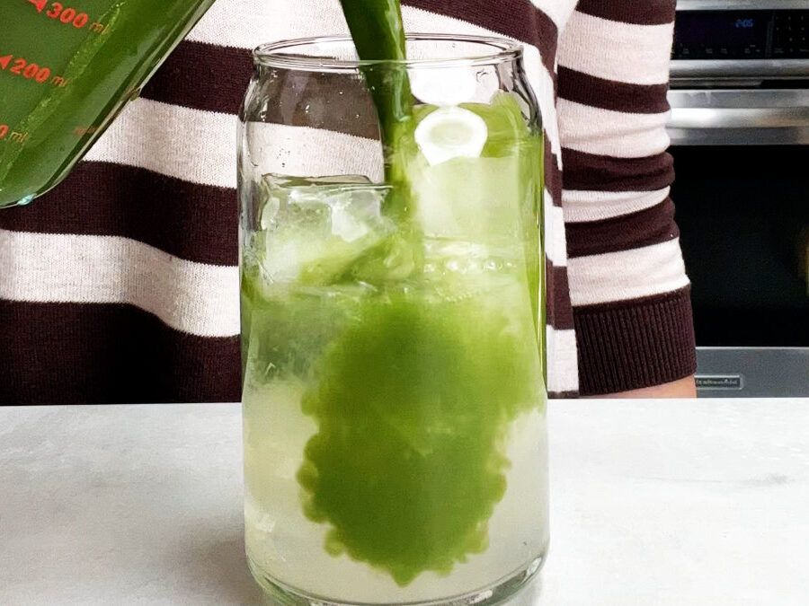 Green tea pouring into a glass of water and ice.